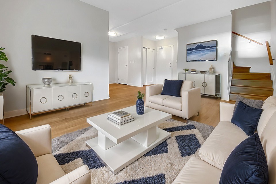 A living room with a white couch, a coffee table, and a television.