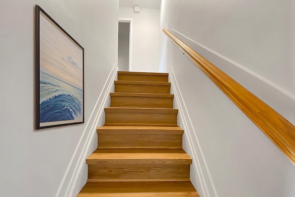 A staircase with a painting of a wave on the wall.