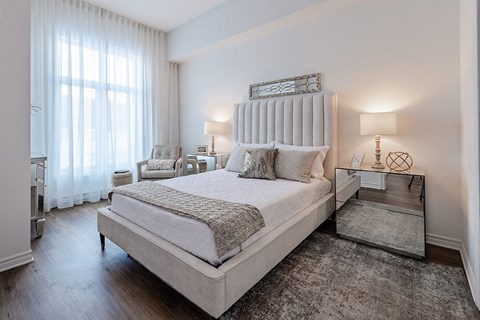 Spacious, modern bedroom with mirrored nightstand at La Voile Pointe-Claire apartments in Pointe-Claire, Quebec