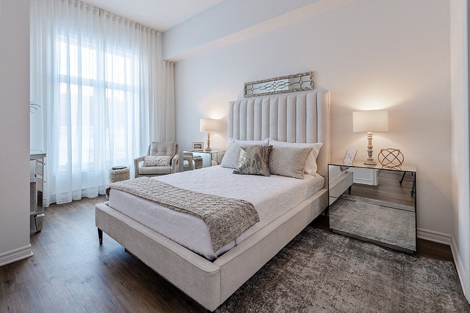Spacious, modern bedroom with mirrored nightstand at La Voile Pointe-Claire apartments in Pointe-Claire, Quebec