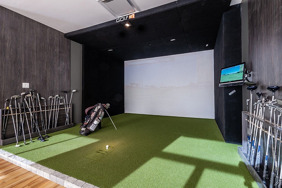 Indoor virtual golf simulator featuring large putting green at La Voile Pointe-Claire apartments in Pointe-Claire, Quebec
