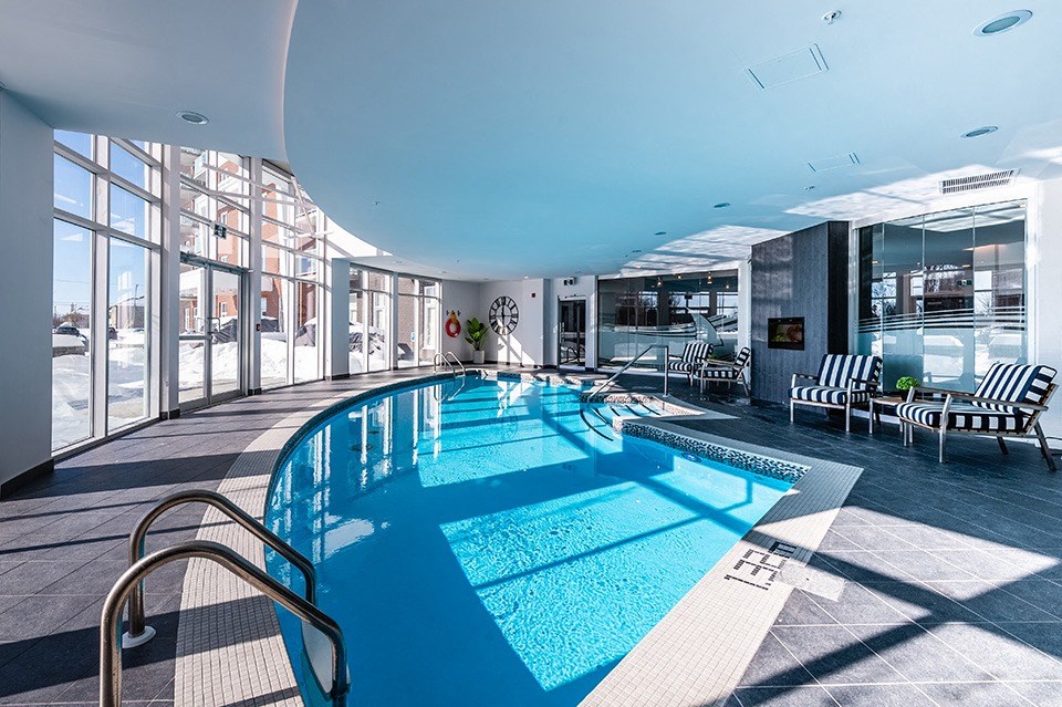 Curved indoor pool with floor to ceiling windows at La Voile Pointe-Claire apartments in Pointe-Claire, Quebec