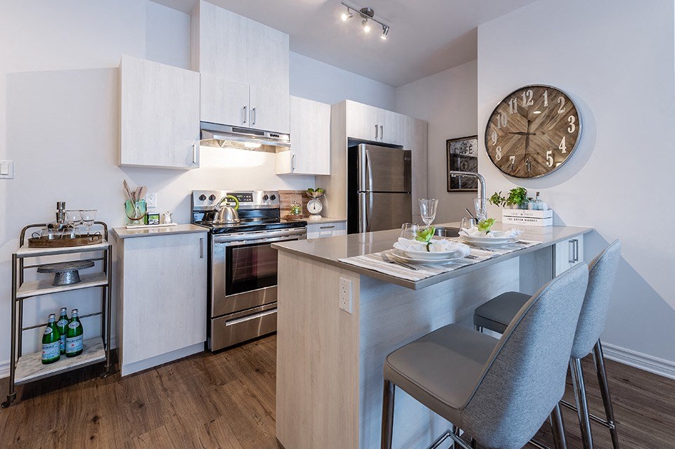 Modern kitchen with stainless steele appliances and quartz countertops at La Voile Pointe-Claire apartments