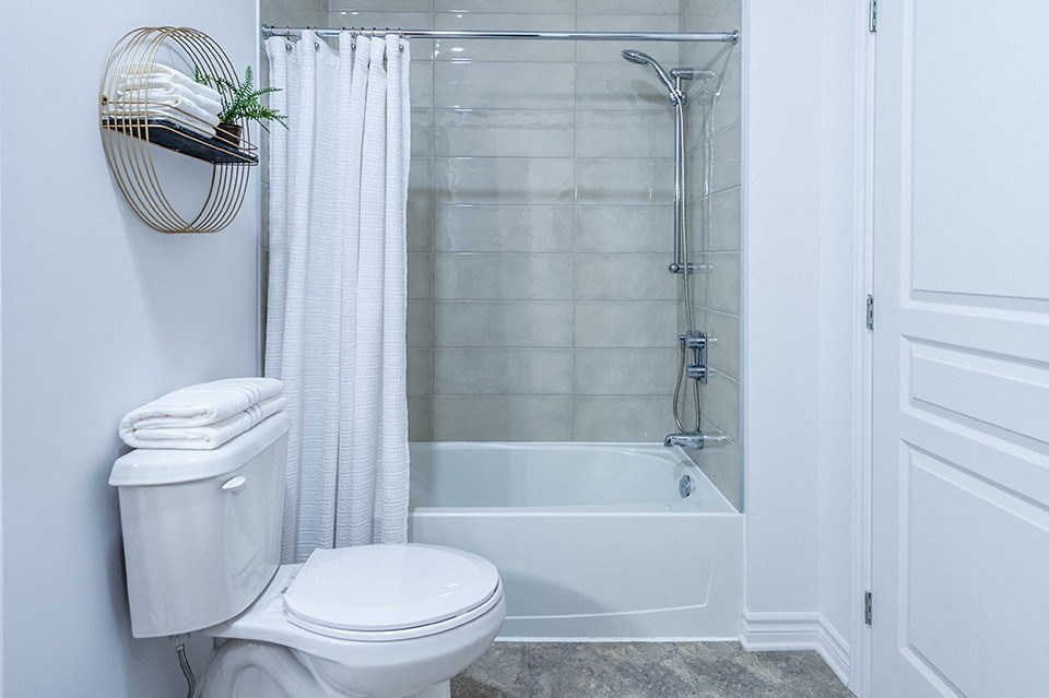 Modern white and grey bathroom featuring a shower tub at La Voile Pointe-Claire apartments in Pointe-Claire, Quebec
