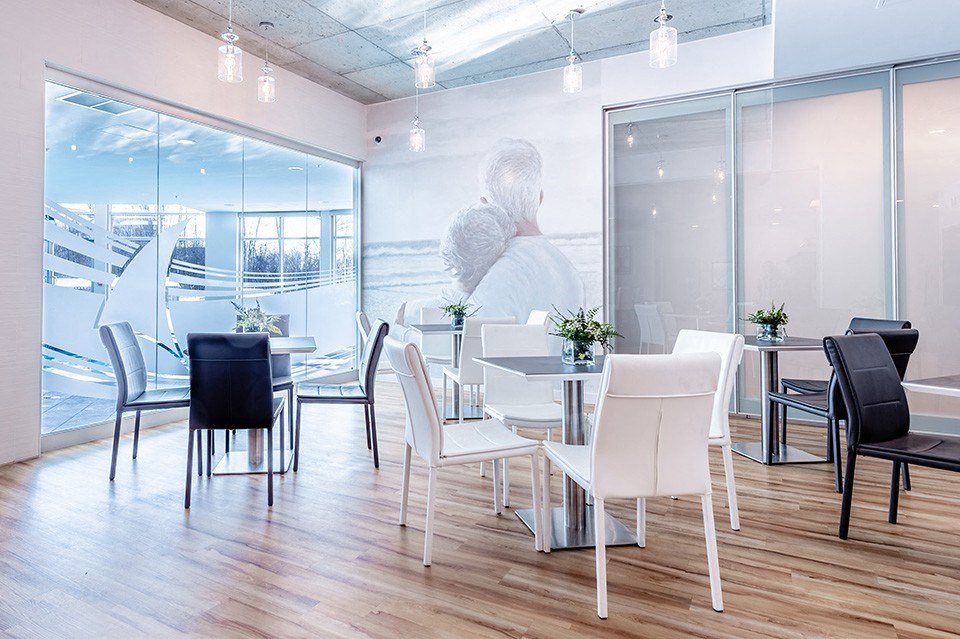 Modern black and white table seating in brightly lit social room at La Voile Pointe-Claire apartments in Pointe-Claire, Quebec