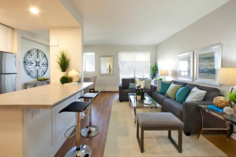 A modern kitchen with a bar and a living room with a couch.