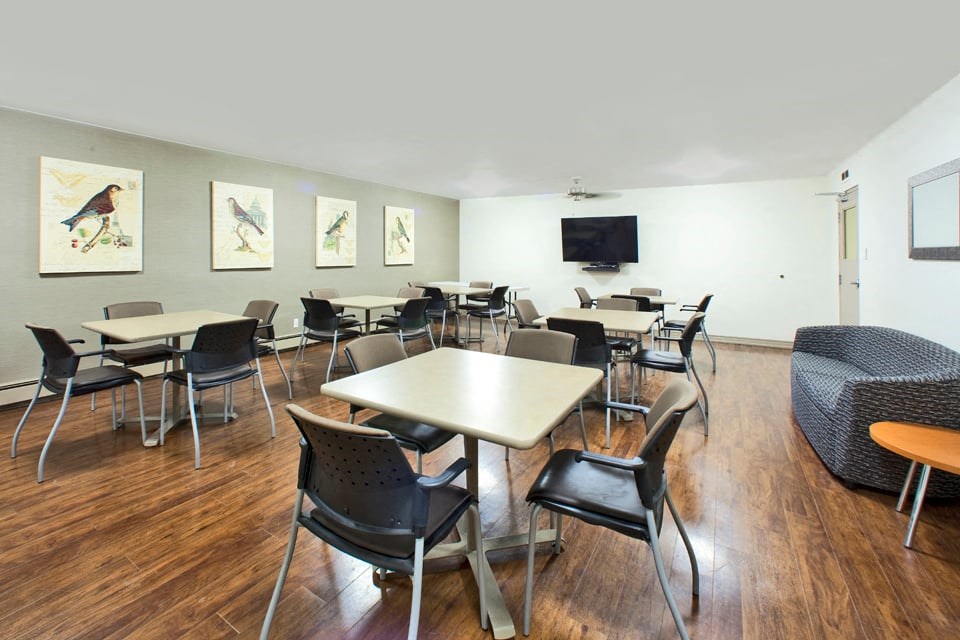 Laura Secord Apartments social room with tables and chairs and a tv in Niagara Falls, ON