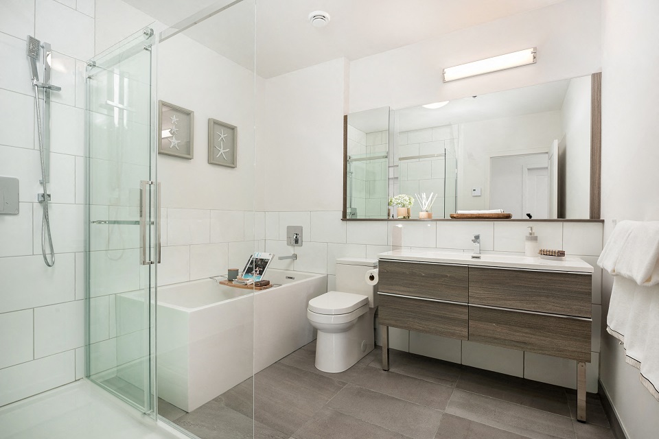 Large bathroom with walk-in shower, tub and vanity with storage at Le Saint-Laurent Apartments in Brossard