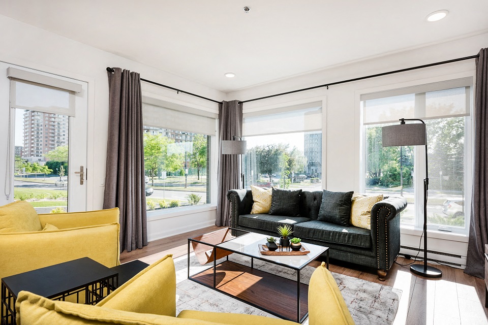 Bright living room with floor to ceiling window in corner suite at Le Saint-Laurent Apartments in Brossard