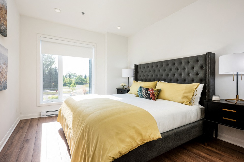 Primary bedroom with large window and blinds included at Le Saint-Laurent Apartments in Brossard