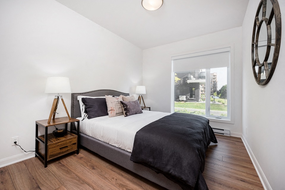 Second bedroom with large windows and blinds at Le Saint-Laurent Apartments in Brossard