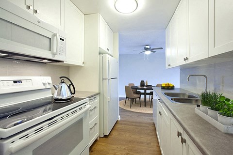A modern kitchen with white appliances and wooden floors.