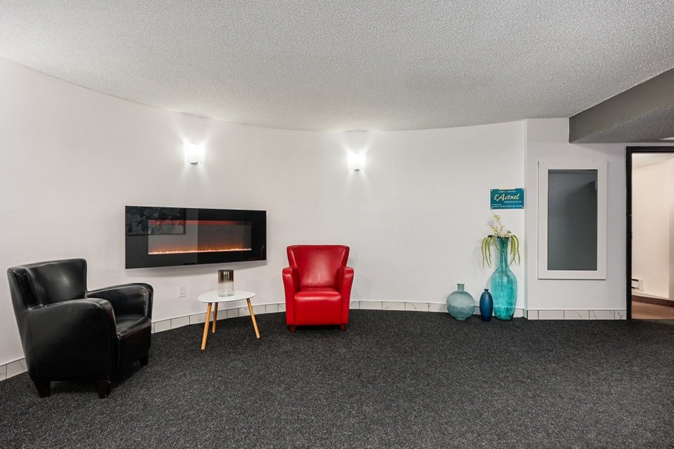 a living room with black carpet and red chairs and a television