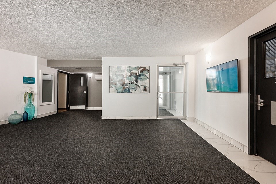 a carpeted hallway with a door and a painting on the wall