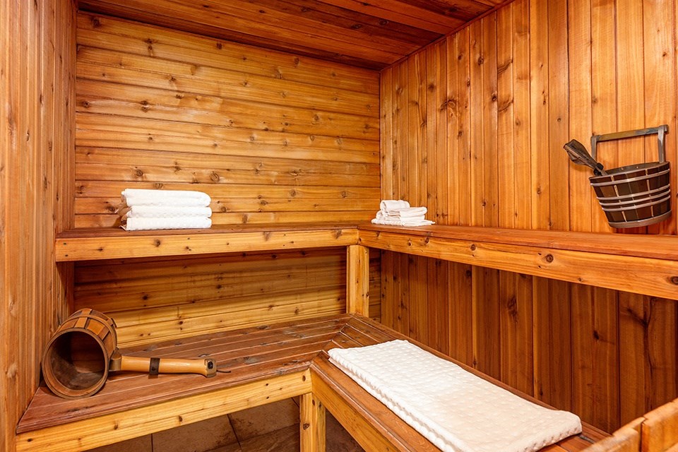 a wooden sauna with a bed and a bucket on the wall