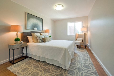 A bedroom with a large bed and a patterned rug.