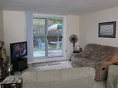 A living room with a couch, chair, and television.