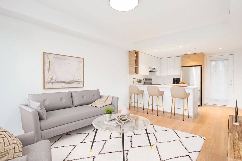 A modern living room with a grey sofa and a coffee table at 388 Kaslo East Village Apartments.