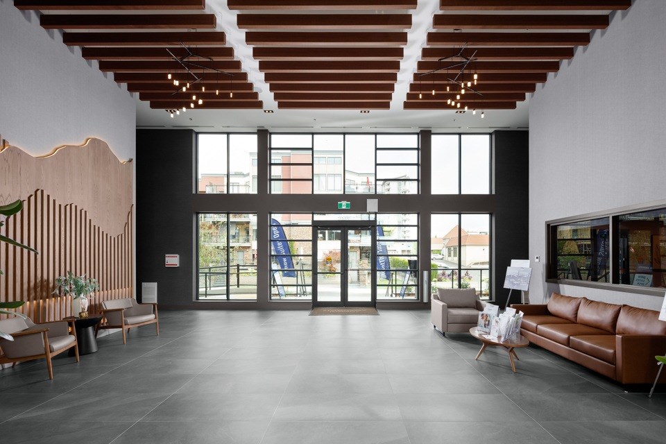 A spacious lobby with a wooden ceiling and a large glass door at The Ambrosi in Kelowna, BC.