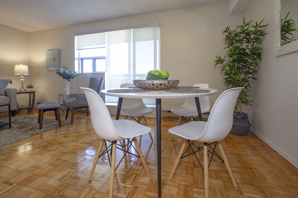 Dining room with white four-seater dining set and plant in a standard suite at Lorneville Apartments in Cornwall, ON