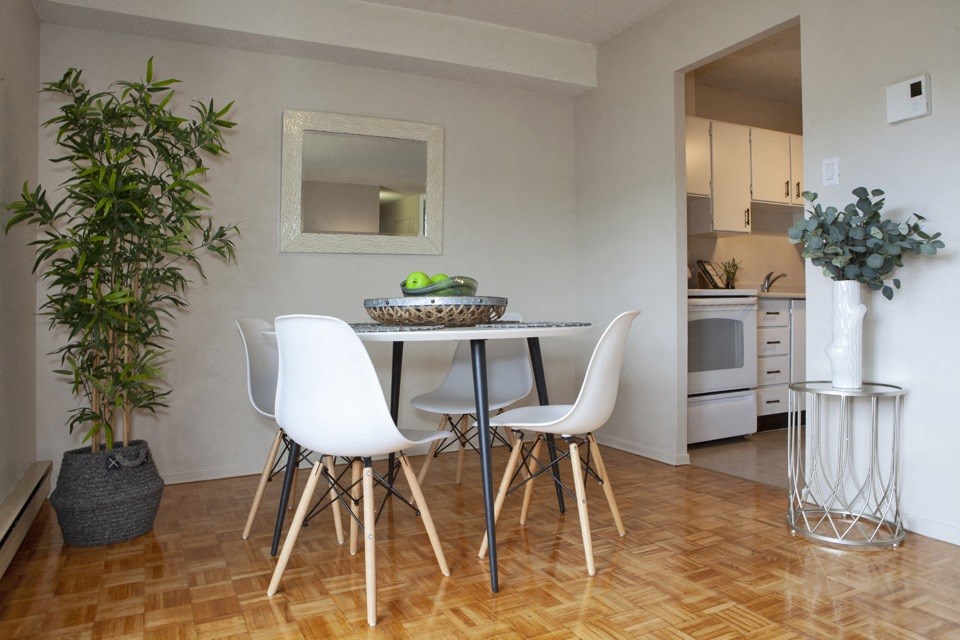 Dining room, with white round table and four white chairs, as seen from the living area, at Lorneville Apartments in Cornwall, ON