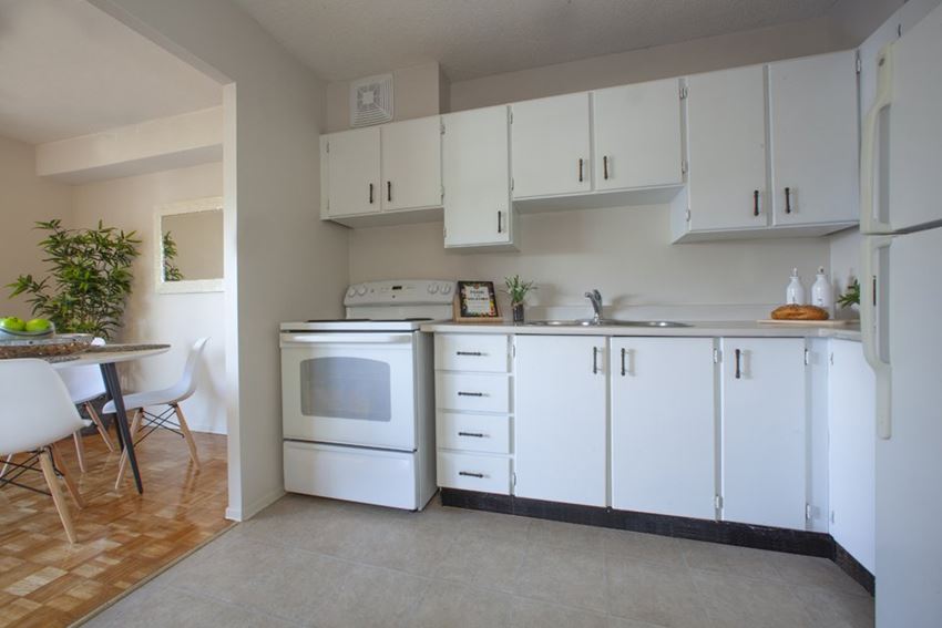 Kitchen with white appliances and white cabinets in a standard suite at Lorneville Apartments in Cornwall, ON