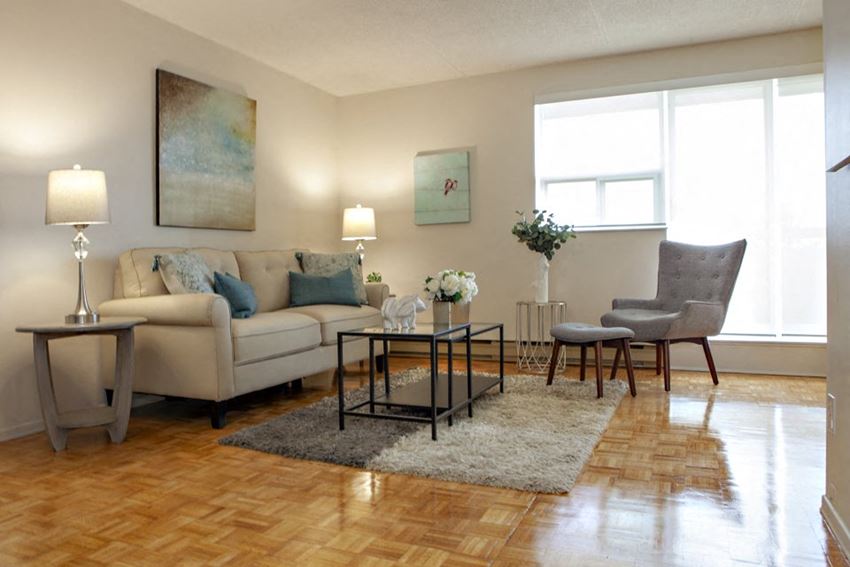 Living room in a standard suite, with light coloured couch and arm chair at Lorneville Apartments in Cornwall, ON