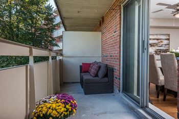 Half of a spacious balcony with potted flowers and patio seating at Lorneville Apartments in Cornwall, ON
