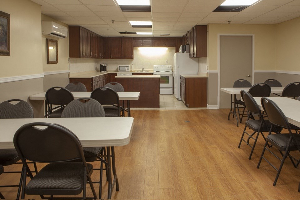 Social room with a full kitchen and ample tables and chairs at Lorneville Apartments in Cornwall, ON