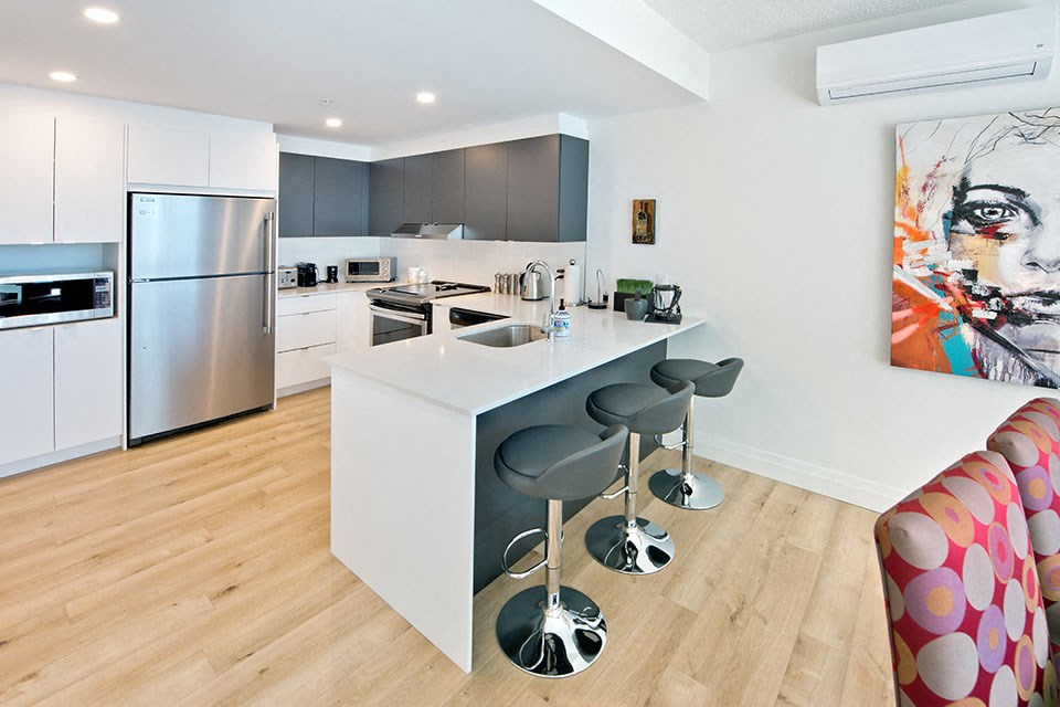 Lumineau in Sherbrooke, QC kitchen with stainless steel appliances and breakfast bar