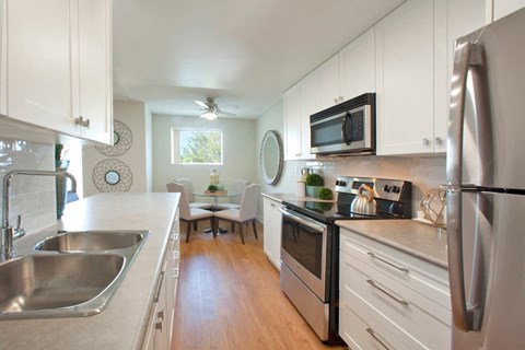 A modern kitchen with white cabinets and stainless steel appliances.