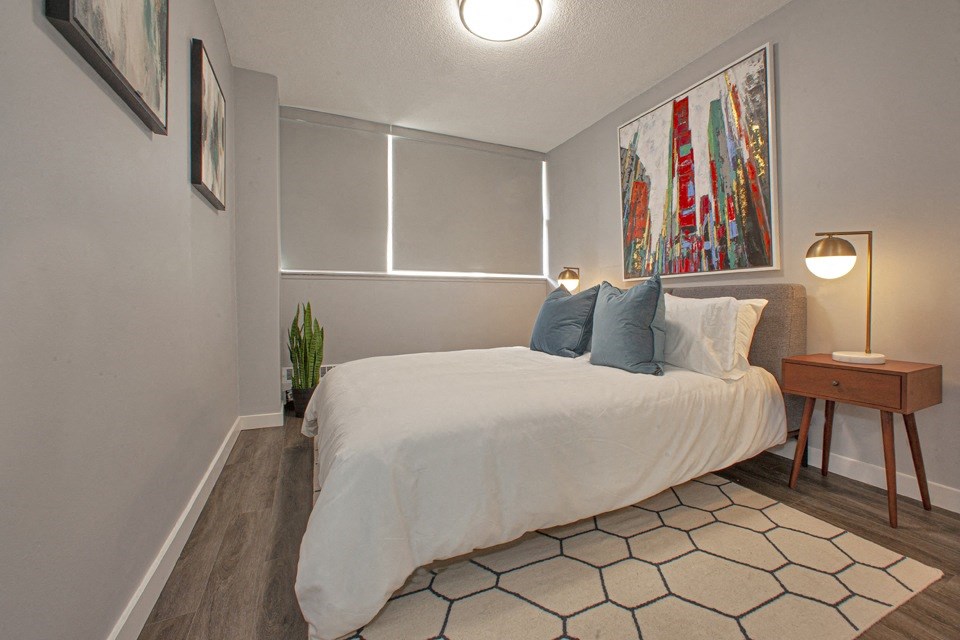 A bedroom with a large bed and a painting on the wall.