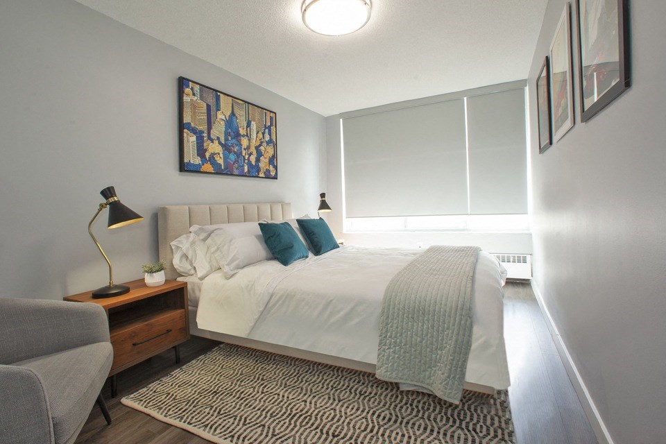 A bedroom with a bed, a chair, and a painting on the wall.