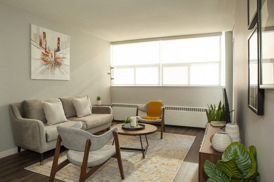 A living room with a grey couch, a yellow chair, and a painting on the wall.