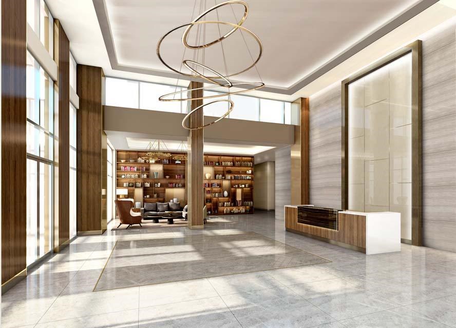 A modern, well-lit lobby with a large circular chandelier and a bookshelf filled with books.