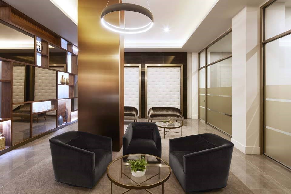 A modern living room with a glass table and black chairs.