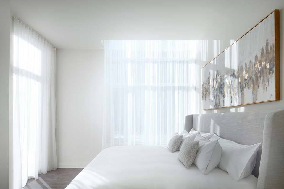 A bedroom with a large bed and a painting on the wall.