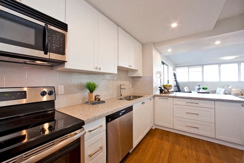 A modern kitchen with white cabinets and stainless steel appliances.