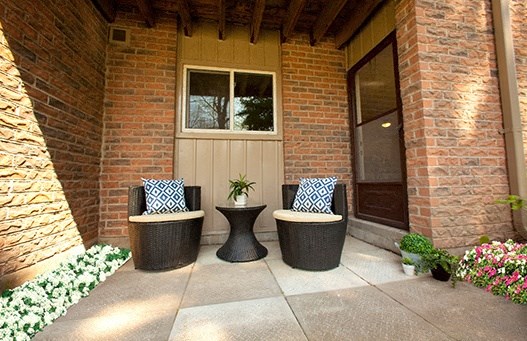 A patio with two chairs and a table with a plant on it.