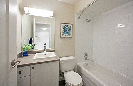 A white bathroom with a toilet, sink, and bathtub.