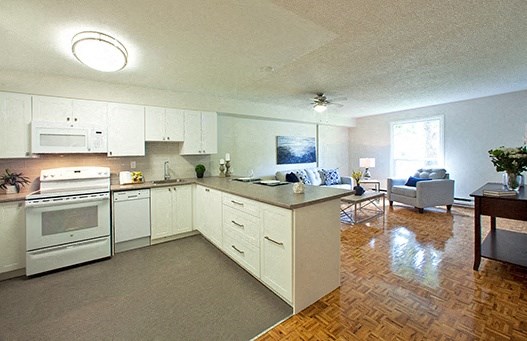 A kitchen with white appliances and wooden floors.