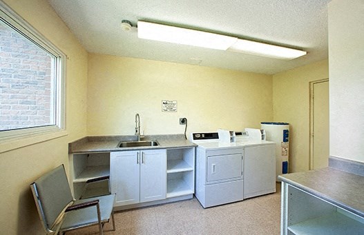 A kitchen with a sink, cabinets, and a chair.