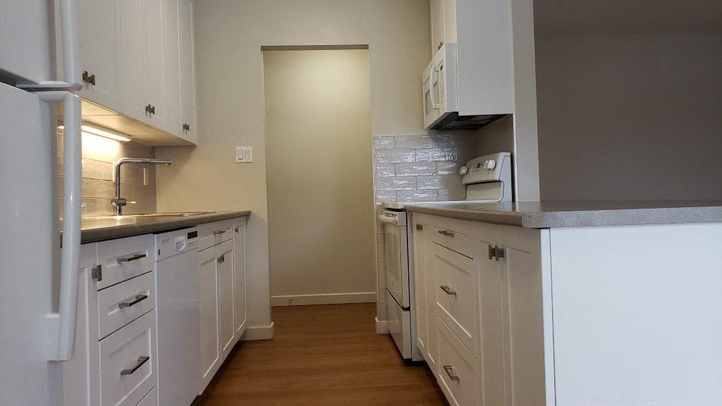 Refinished kitchen, showing storage island, in a refinished kitchen in an open concept layout at Moira Apartments in Belleville, ON.