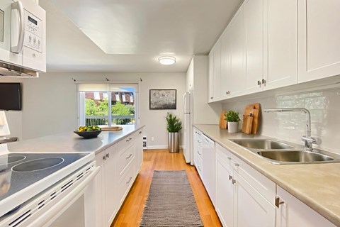 A modern kitchen with white cabinets and a grey countertop.