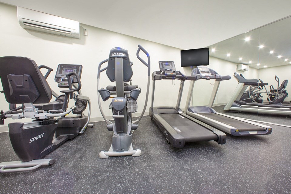 Gym with various cardio machines and a TV at Northgate Tower Apartments in Woodstock, Ontario