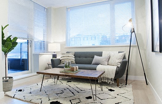 Living room with wide window above the couch. A door to the balcony is on the left.