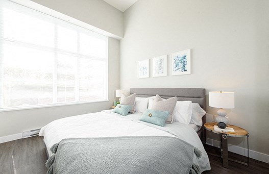 Luxury living in New Westminster begins at Novare Bedroom with open blinds, allowing the sunlight to filter onto the bed