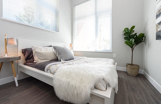 Bed with fluffy white throw blanket at the foot of the bed