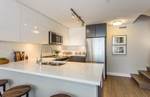 a white kitchen with a sink and a refrigerator