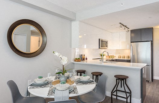 Dining room with round mirror and set table seating four people